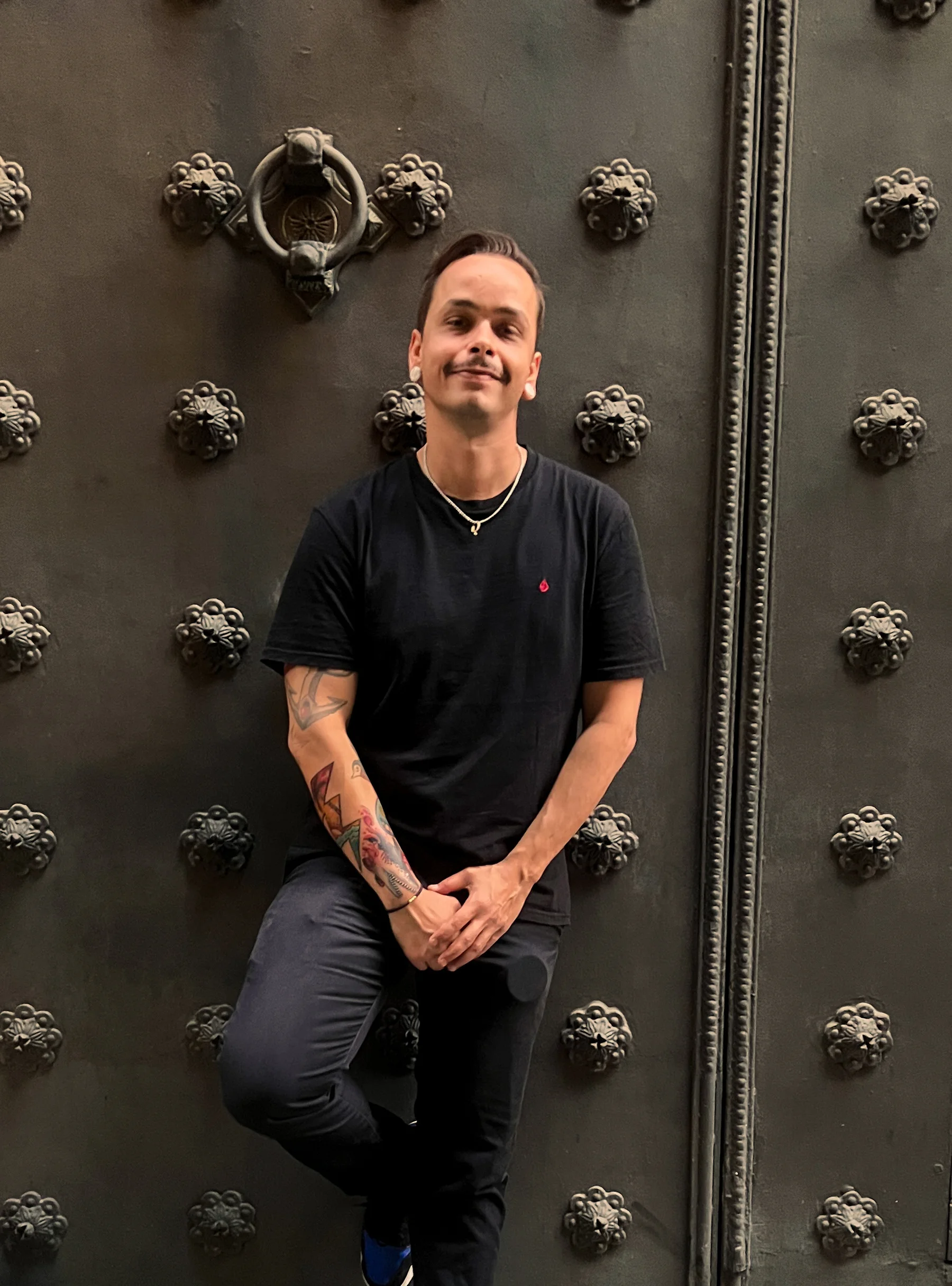 Dave mit frisch tätowiertem Arm, angelehnt an eine Nietentür