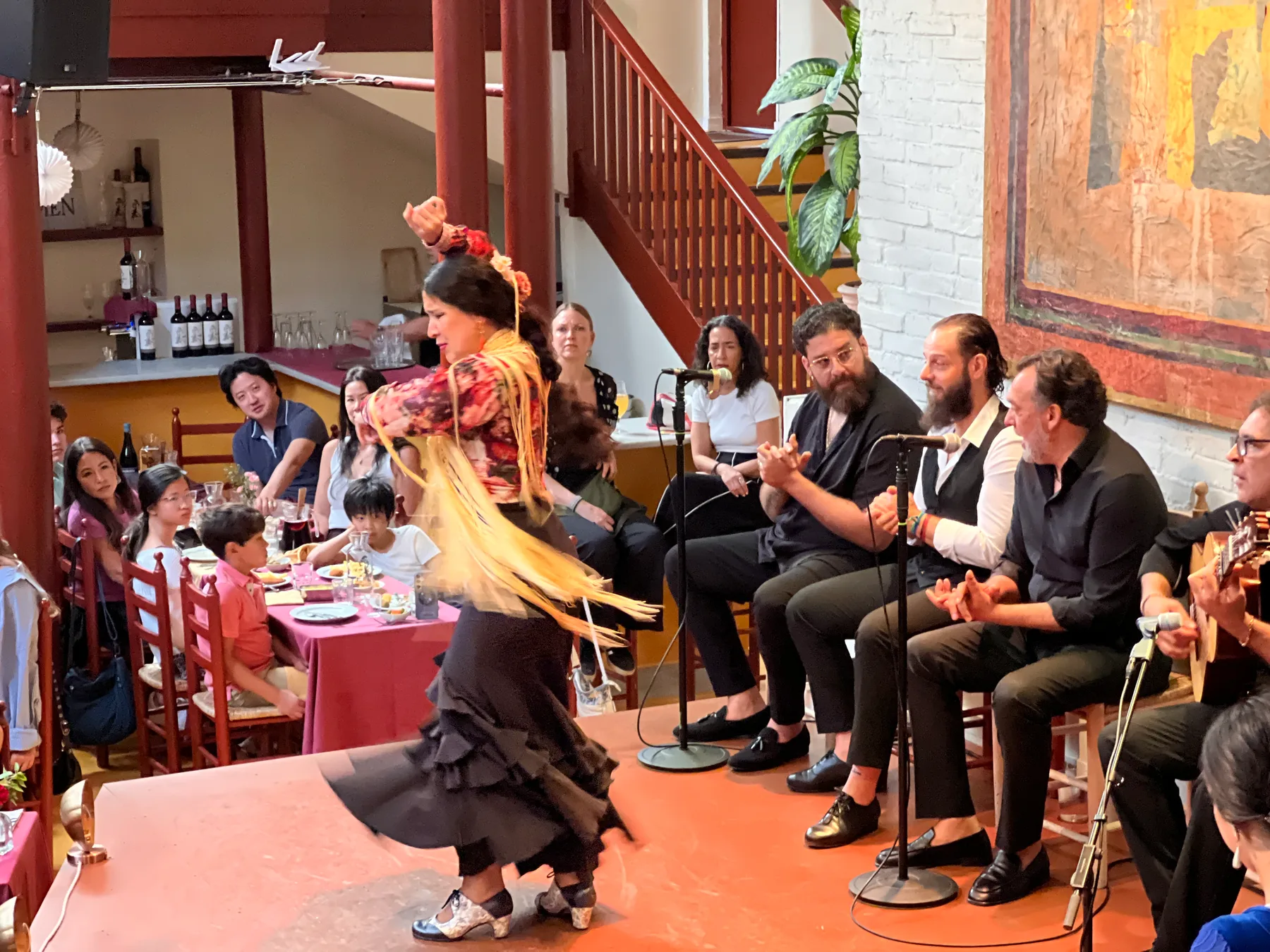 Flamenco-Tänzerin mit gelbem Fransenschal, dahinter der Sänger