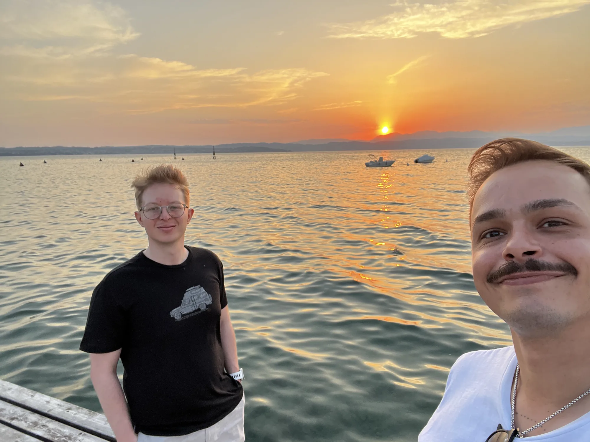 Zwei Freunde im Gegenlicht des Sonnenuntergangs am See